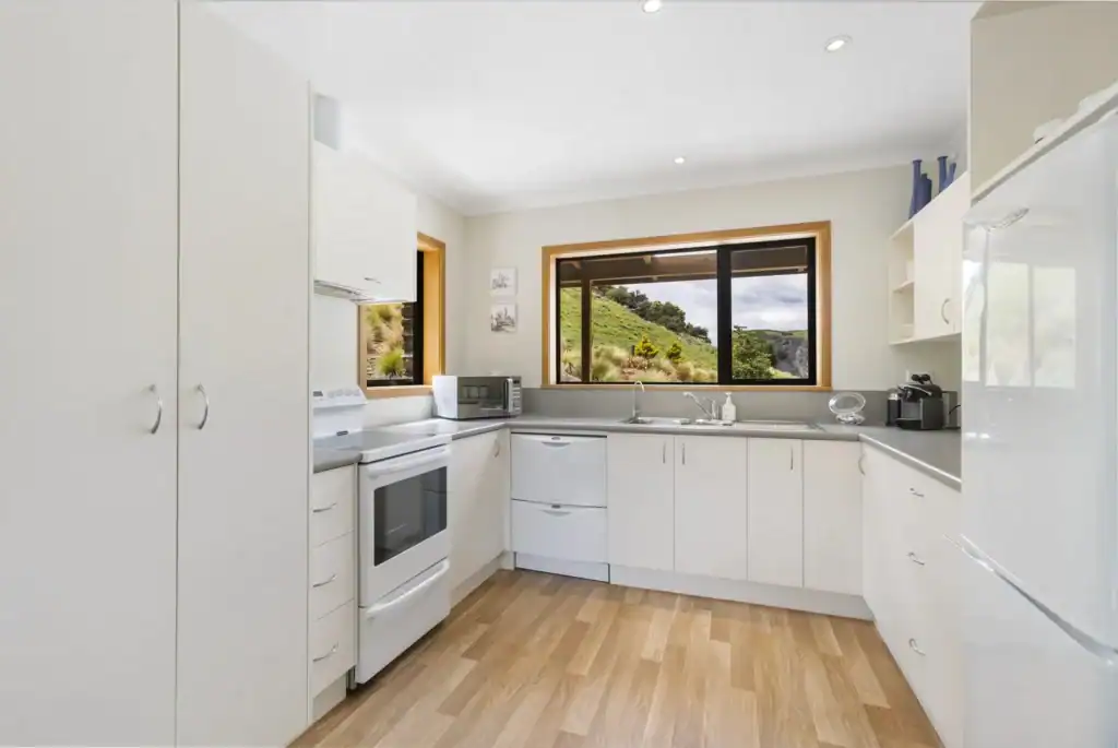 Modern kitchen with white cabinets and large windows overlooking scenic hills, ideal for a vacation rental at Judge & Jury Village. Perfect for relaxing and enjoying nature.