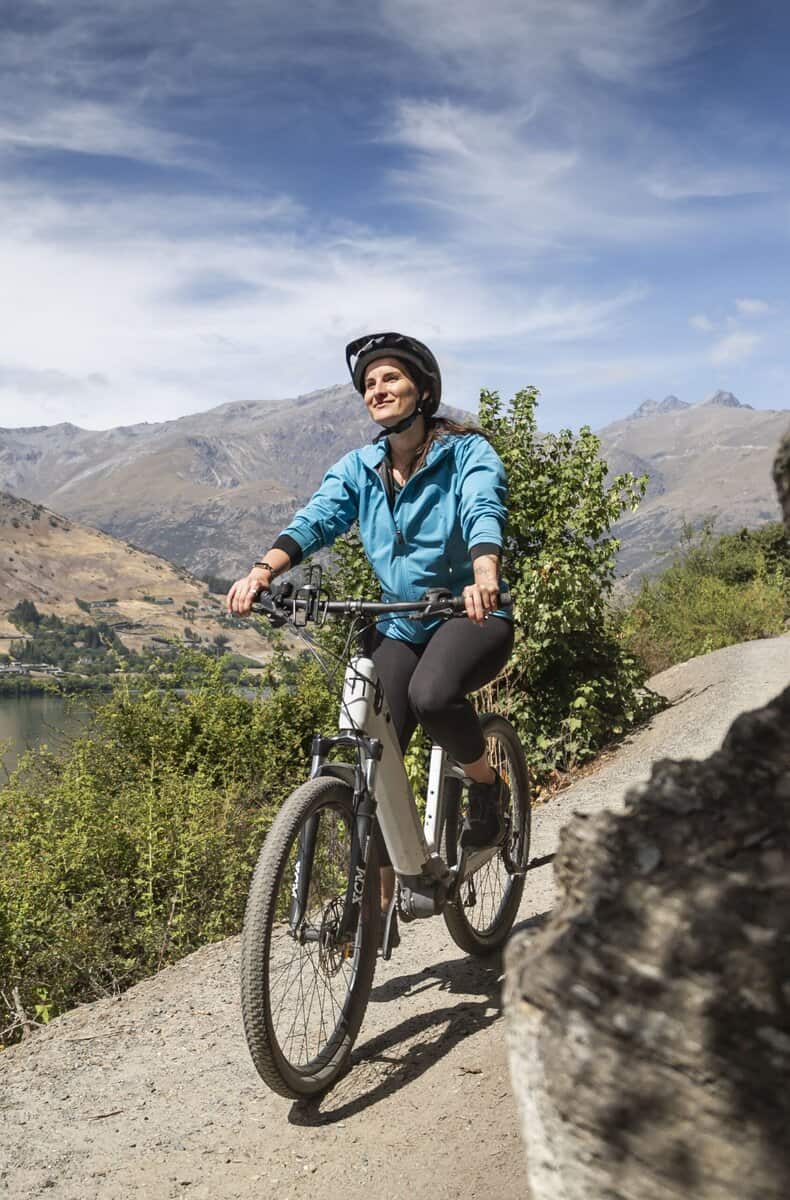 Bright woman mountain biking on scenic trail in Judge & Jury Village, New Zealand.